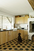 Einbauküche mit Holzfronten und sechseckigem Bodenfliesen, Hund vor gemauertem Kamin