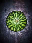 Eine Wassermelone auf grauem Untergrund (Aufsicht)