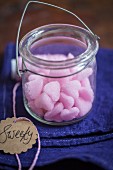 Pink sugar hearts in a glass jar with a written gift tag