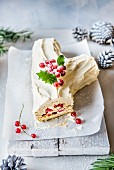 A white chocolate Yule log for Christmas with redcurrants and holly
