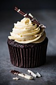 A chocolate cupcake with white chocolate cream and chocolate curls