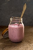 Blueberry yoghurt in a glass jar with a spoon