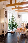 Carved tray table, lit candles and sweets in front of Christmas tree
