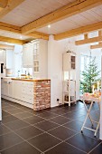 Brick-built counter in country-house kitchen adjoining open-plan living area with Christmas tree in background