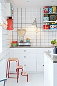 weiße Einbauküche mit Retro Küchenwaage und bunten Blechdosen auf String-Regal