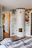 Eleganter, kunsthandwerklicher Kachelofen in Schlafzimmerecke mit Blumentapete