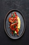 Pork escalope in sweet and sour plum sauce with ham crisps and polenta