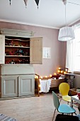 Vintage wooden bed, fairy lights, vintage cupboard and contemporary toys in child's bedroom