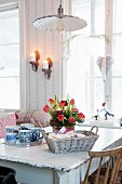 Advent arrangement of red tulips, bread basket and tray of cups on dining table
