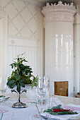 Festively set table in front of Swedish tiled stove