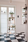 Christmas decorations on step ladder on chequered floor