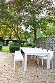 Kiesplatz mit weißen Outdoormöbeln vor Gabionzaun im Garten