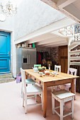 Dining table, vintage chairs and blue panelled door in loft apartment