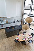 Place settings on oval dining table in open-plan kitchen of loft apartment