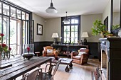 Gemütliche Ledersessel und rustikale Tische in Wohnbereich mit traditionellem Flair und offener Balkontür