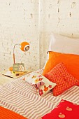 Orange pillows on bed and retro bedside lamp
