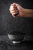 A hand drizzling black rice into a bowl