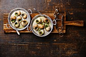 Bourgogne Escargot Snails with garlic herbs butter in aluminum pan on rustic wooden background