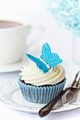Schokoladen-Cupcake, dekoriert mit einem blauen Zucker-Schmetterling