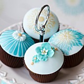 Blau, weiss und goldverzierte Hochzeits-Cupcakes auf einer Etagere