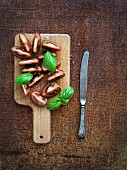 Fresh tomato slices with salt and basil leaves on wooden chopping board
