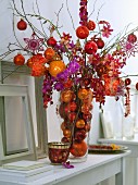 Weihnachtsstrauß mit Orchideen und Christbaumkugeln in Rottönen