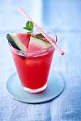 A watermelon drink in a glass with a straw