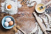Backzutaten für Croissants: Brauner Zucker, Eier, Mehl, Butter und Schokodrops auf Holzuntergrund