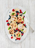 Russian and Ukranian cuisine: Syrniki or cottage cheese pancakes with fresh forest berries and sour cream sauce
