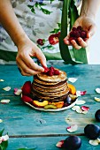 Girl putting raspberries on the top of pancakes