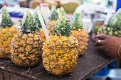 Pineapples with their tops sliced off with straws at a market