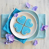 Vier Kekse in Herzform mit blauem und weißem Zuckerguss dekoriert