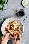 Spaghetti with aubergine and tomatoes being twirled onto a fork