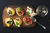 Bruschetta with fruits and tomatoes served with a glass of white wine