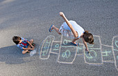Young Girl Playing Hopscotch on Pavement