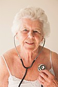 Elderly woman using a stethoscope