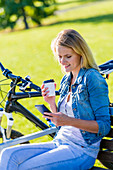 Woman using cell phone with coffee
