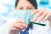 Scientist pouring green liquid into a cup