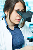 Lab technician using microscope