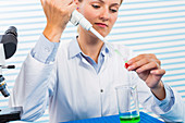 Female chemist using pipette in lab