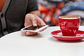 Person using smartphone with coffee