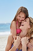 Mother and daughter laughing on beach