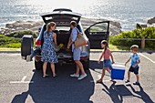 Family unpacking the car by the beach