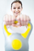Smiling young woman holding kettlebell