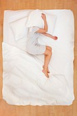 Woman lying in bed with pillow over head