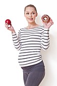 Pregnant woman holding apple and doughnut