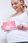Pregnant woman holding pink baby scan