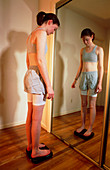 View of an anorexic woman looking in a mirror
