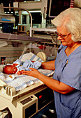 Maternity nurse putting newborn baby in incubator