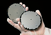Gloved hands holding processed silicon wafers